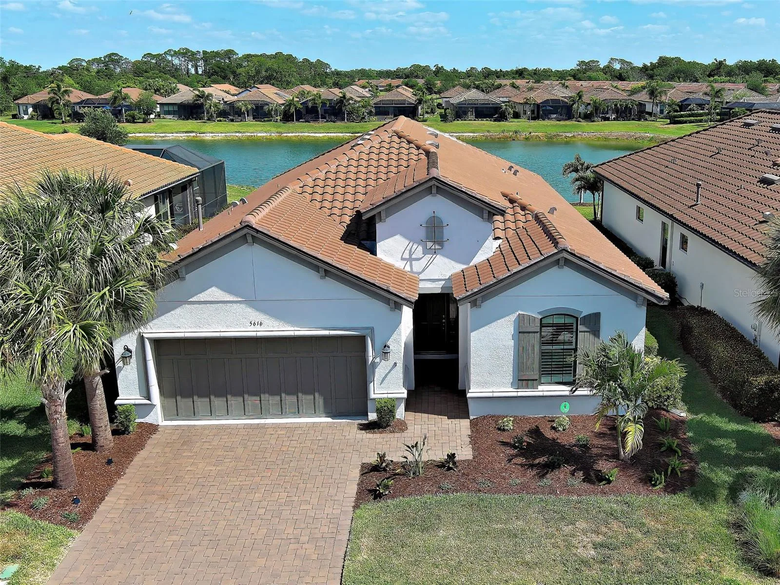 Gorgeous Florida-style home with a tile roof, driveway pavers on a pond.